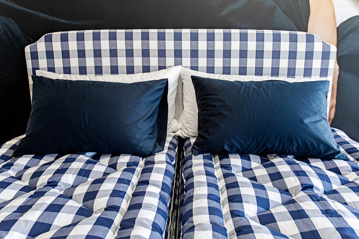 Hästens bed in the signature blue-and-white check, with a matching headboard and navy pillows